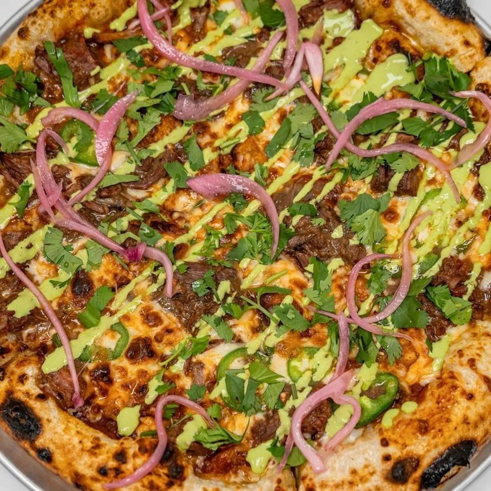 Birria-style beef pizza with cilantro, pickled onion and avocado crema
