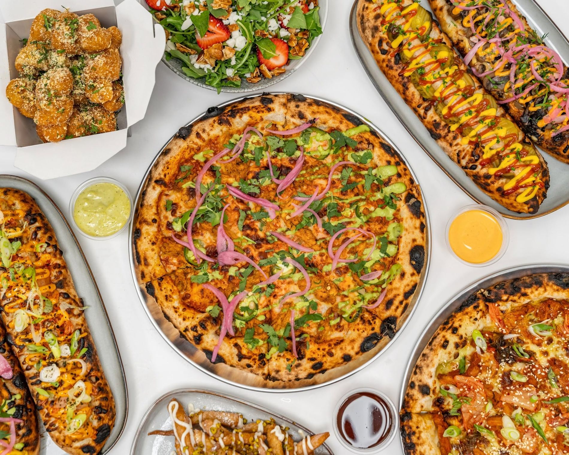 A spread of Baked Columbia pizzas, garlic knots, salad and dips