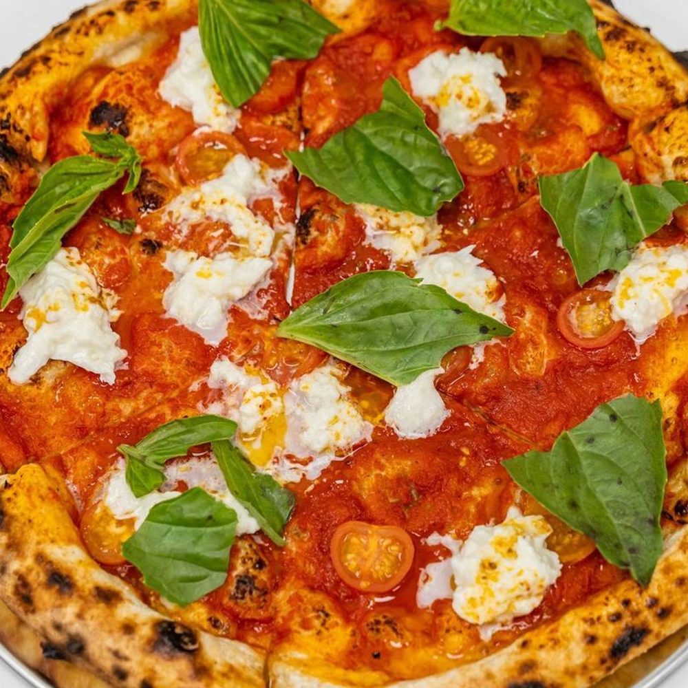 Margherita pizza with tomato sauce, torn burrata and fresh basil