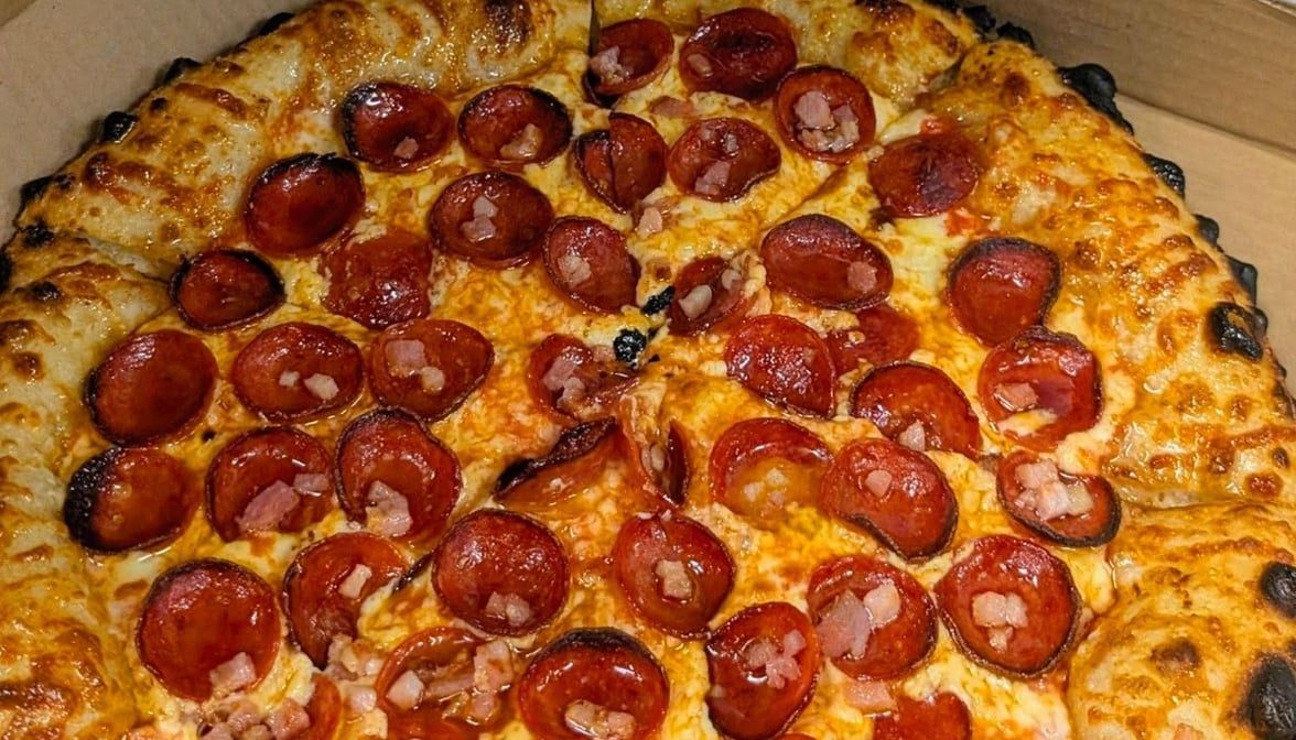 Close-up of a pepperoni and bacon sourdough pizza with blistered, leopard-spotted crust